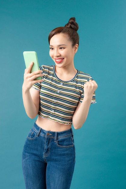 Happy joyful girl holding mobile phone and celebrating a win