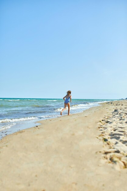 Bambina allegra felice correre sulla spiaggia