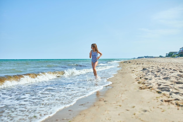 Bambina allegra felice correre sulla spiaggia