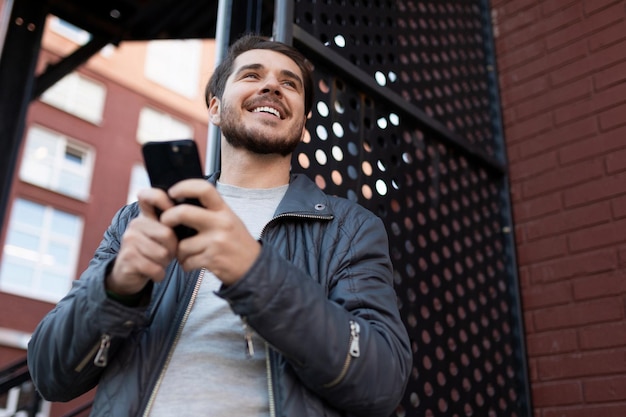 Happy joyful man with a smile on his face with a phone in his hands outside