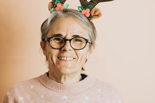 Happy Joyful senior oude witte haren vrouw met rendier hoorns hoed glimlachen tijdens het spelen en plezier maken. staat tegen een gekleurde achtergrond. Kerstkleding dragen. Ruimte kopiëren. Advertentie ruimte