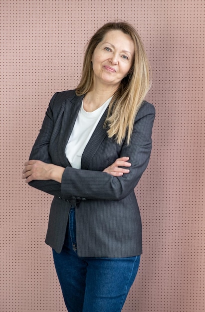 Happy joyful woman in casual posing over pink studio background Portrait of cheerful successful middle aged business lady with arms folded smiling at camera Female portrait concept