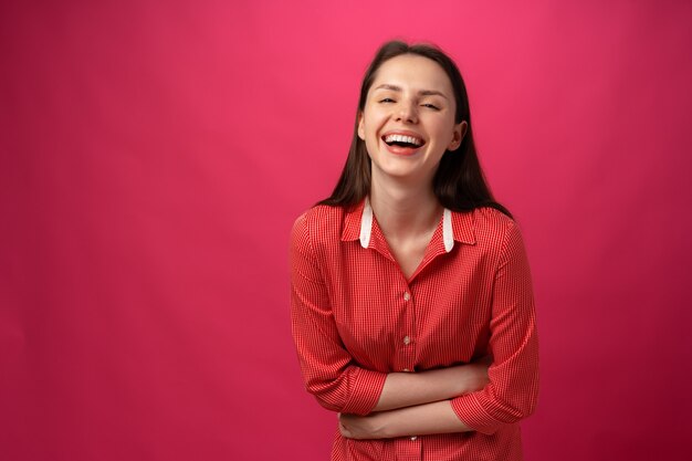 Happy joyful young woman smiling against pink background