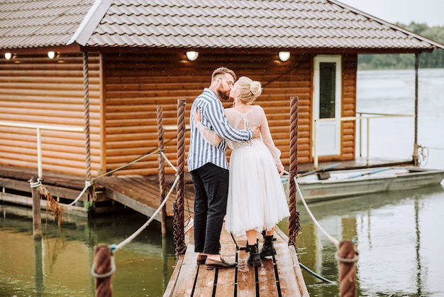 The happy just married tenderly kissing and huging on the wharf.The bride and groom they stand and pose on the pier.