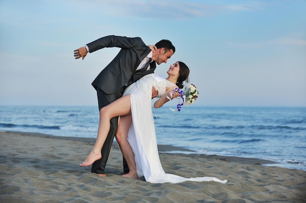 happy just married young couple celebrating and have fun at beautiful beach sunset