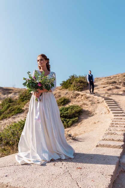 クリミアセヴァストポリの美しいビーチの夕日を祝って楽しんで幸せな結婚したばかりの若い結婚式のカップル