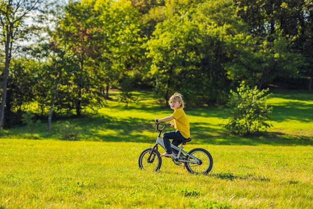 Happy kid boy of 5 years having fun in the park with a bicycle on beautiful day.