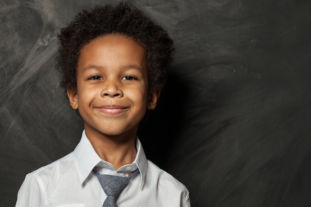 Happy kid boy on blackboard background Smiling child face close up portrait