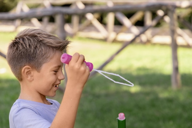 Ragazzo felice che soffia bolle di sapone in un parco