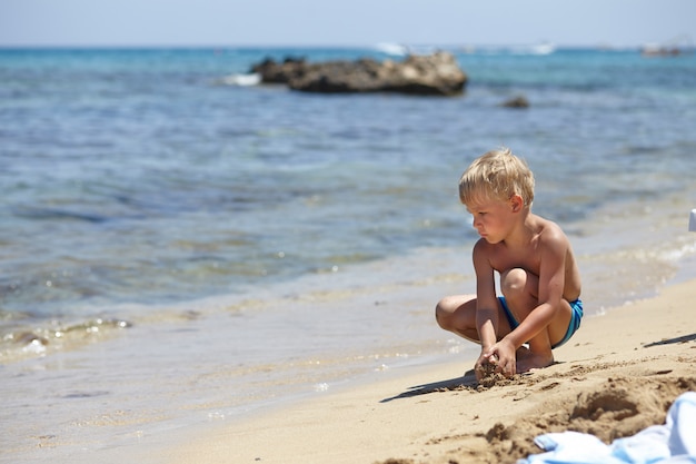 Happy kid boy playing on a beach