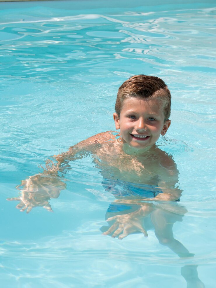 Happy kid boy swimming in pool resort