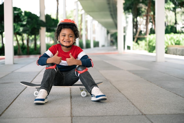 Happy kid boy with afro hair and skateboard in the park