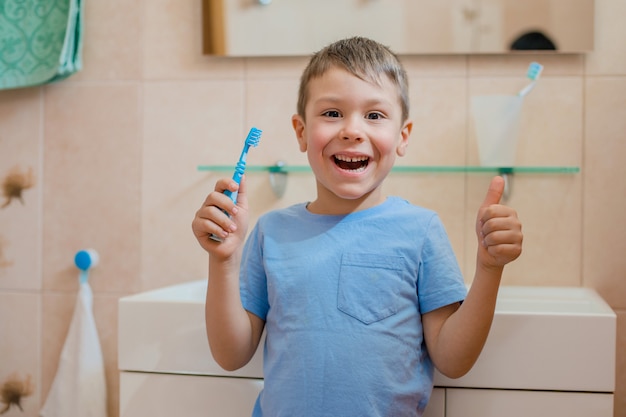 Happy kid or child brushing teeth in bathroom.