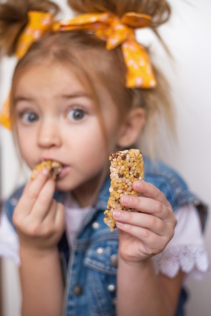 Foto il bambino felice mangia una barretta di frutta uno spuntino sano