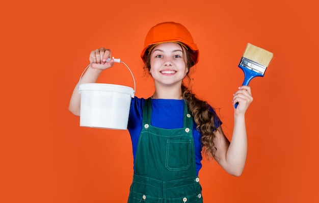 Happy kid engineer with painting bucket and brush tool in hard hat hobby