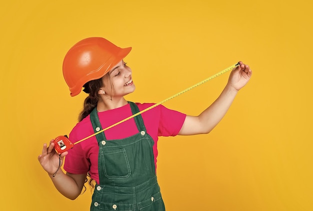 Happy kid engineer with tape measure tool in hard hat measure