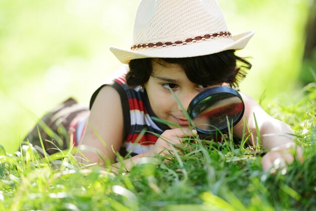 Happy kid exploring nature with magnifying glass