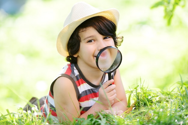 幸せな子供が虫眼鏡で自然を探索する