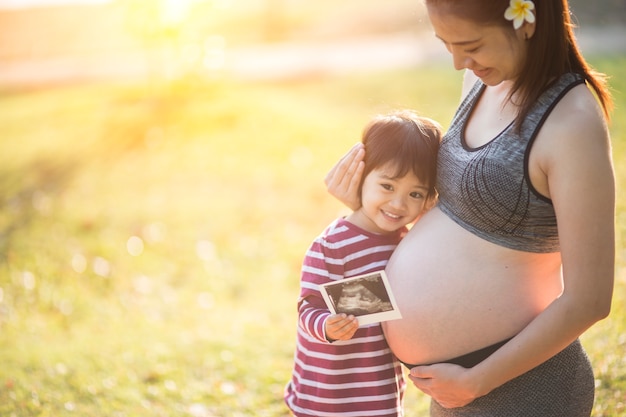Счастливый парень девочка обнимает беременной матери живот, беременность и новая концепция жизни