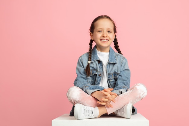 Happy kid girl isolated on pink studio background Looks happy cheerful sincere Copyspace Childhood education emotions concept