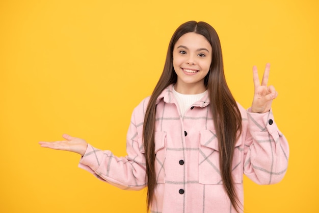 Счастливая девочка в розовой клетчатой рубашке представляет рекламное пространство для копирования продукта