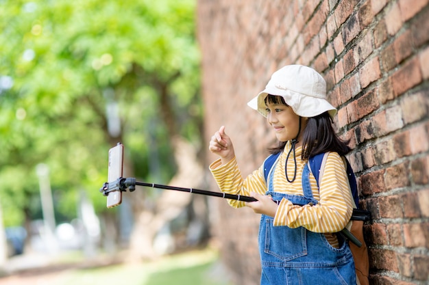 自撮り写真を撮る幸せな子供の女の子。スマートフォンで自分撮り写真を撮る