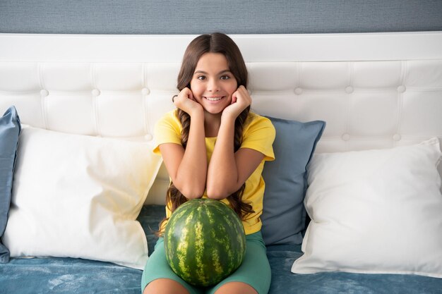 Happy kid holding fresh ripe water melon fruit at home childhood