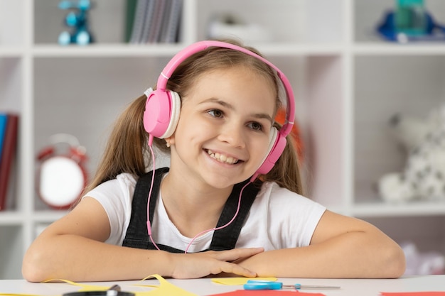 Happy kid listen music in headphones at school lesson in classroom, education online.