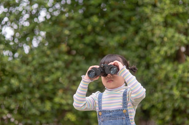 写真 先を見据えて幸せな子供。スパイグラスで子供を笑顔。旅行と冒険のコンセプト。自由、休暇