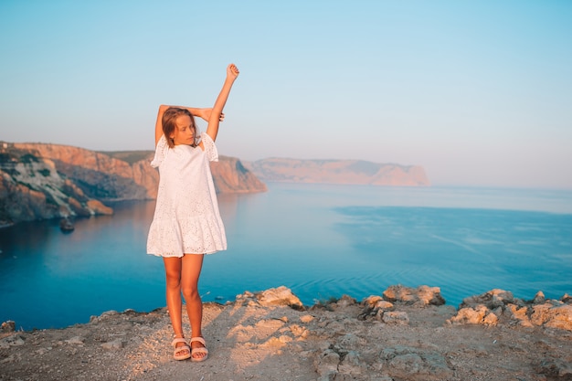 Happy kid outdoor on edge of cliff seashore