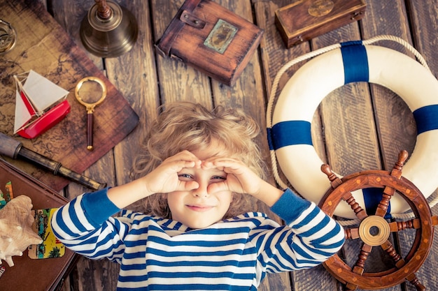 Happy kid playing with nautical things. Child having fun at home. Travel and adventure concept. Unusual high angle view portrait