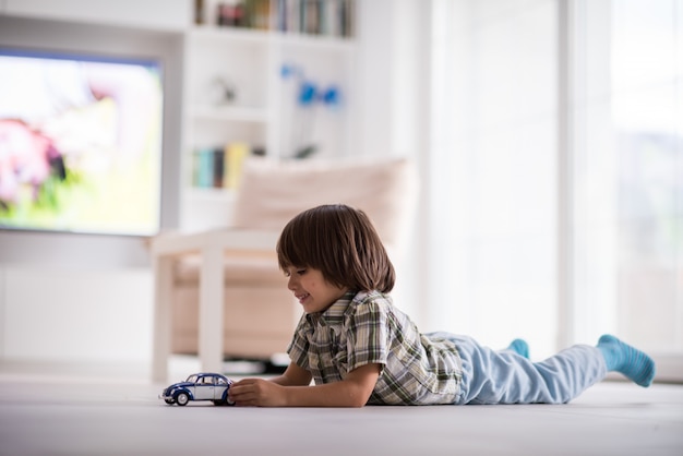 家で古い車のおもちゃで遊んでいる幸せな子供