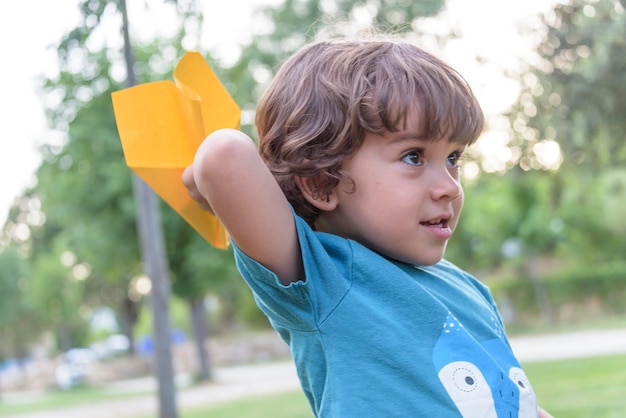 Happy kid playing with toy airplane against summer sky background at sunset