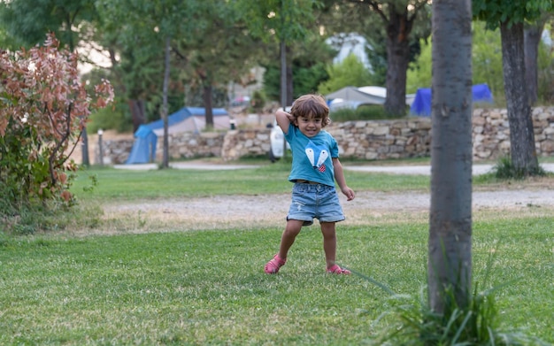 Bambino felice che gioca con l'aeroplano giocattolo sullo sfondo del cielo estivo al tramonto