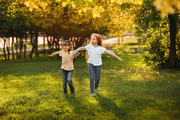 Bambino felice che gioca con l'aeroplano giocattolo di legno nel parco di primavera