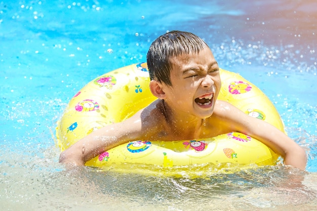 Happy kid on safety ring in swimming pool