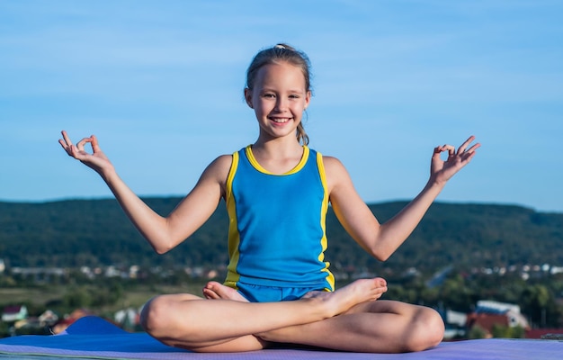 Happy kid in sport training clothes workout in meditation yoga pose harmony