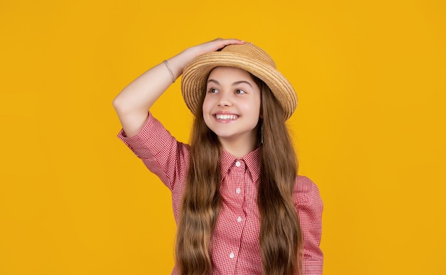Happy kid in straw hat on yellow background
