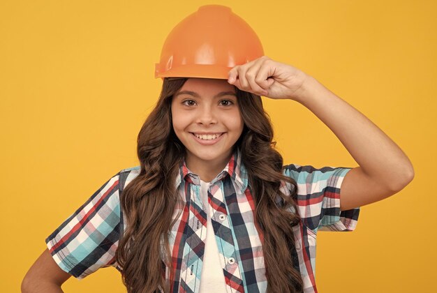 Happy kid with curly hair in construction helmet architect