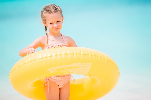 Happy kid with inflatable rubber circle having fun on the beach