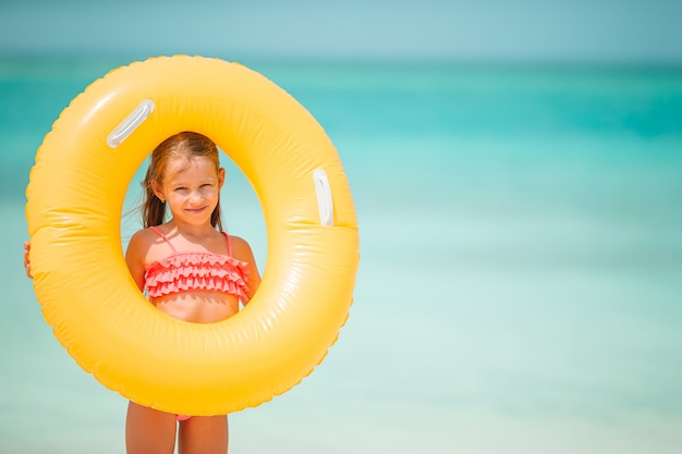 Bambino felice con il cerchio di gomma gonfiabile divertendosi sulla spiaggia