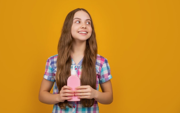 Happy kid with liquid soap bottle on yellow background