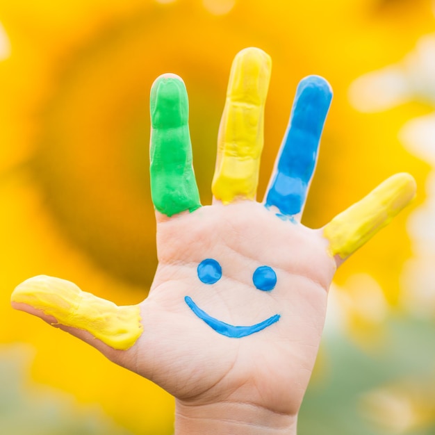 Happy kid with smiley on hand against spring yellow sunflower background