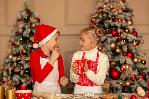 幸せな子供たちはクリスマスのためにジンジャーブレッドのクッキーを焼く