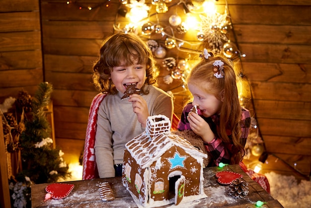 Happy kids eating Christmas gingerbread house