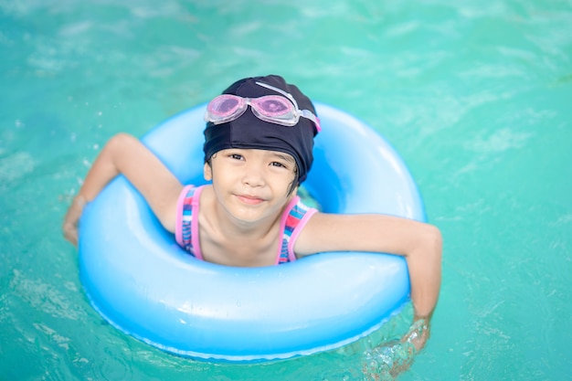 Happy kids girl child sleep on life ring safety for swimming in swimming pool