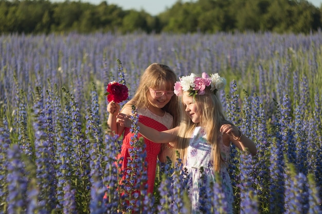 自然の夏の草原で花と幸せな子供女の子。花輪の女の子。子供たちの笑顔。