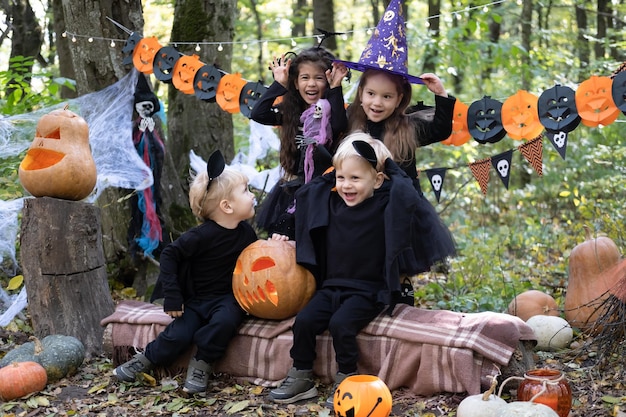 屋外のハロウィーンの装飾で楽しんでいるハロウィーンの衣装で幸せな子供たち