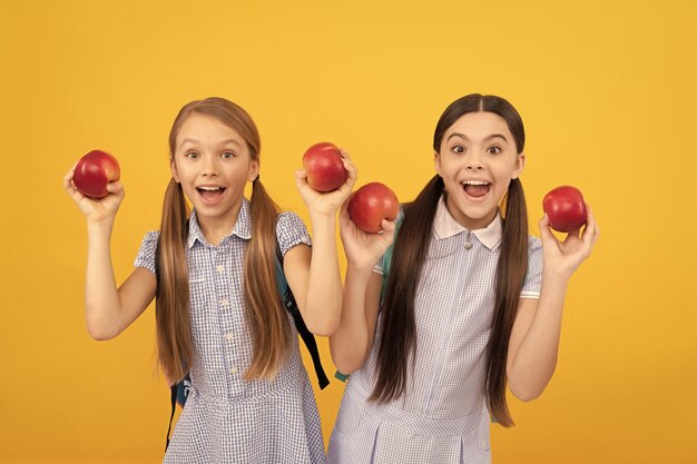 행복한 아이들은 건강한 학교 간식 노란색 배경 학교 급식을 위해 사과를 들고 있습니다.