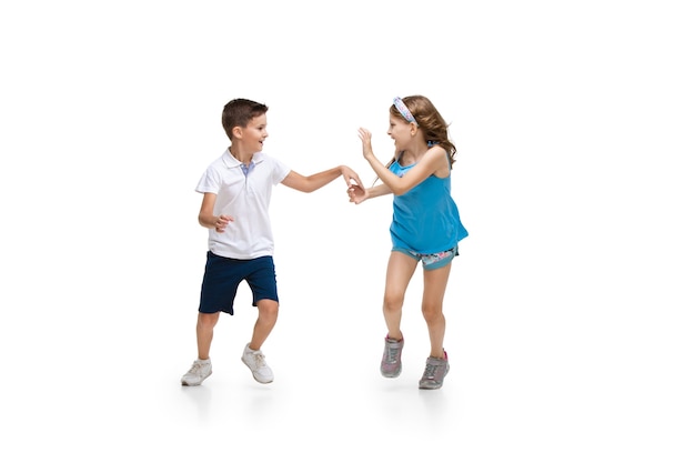 Happy kids, little and emotional caucasian boy and girl jumping and running isolated on white